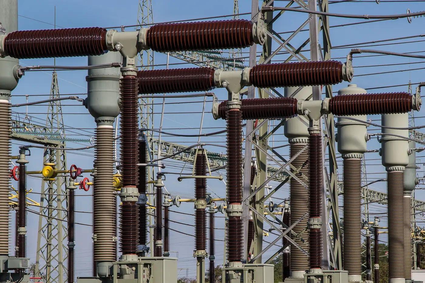 Close-up of tall porcelain bushings and insulator stacks on substation switchgear.
